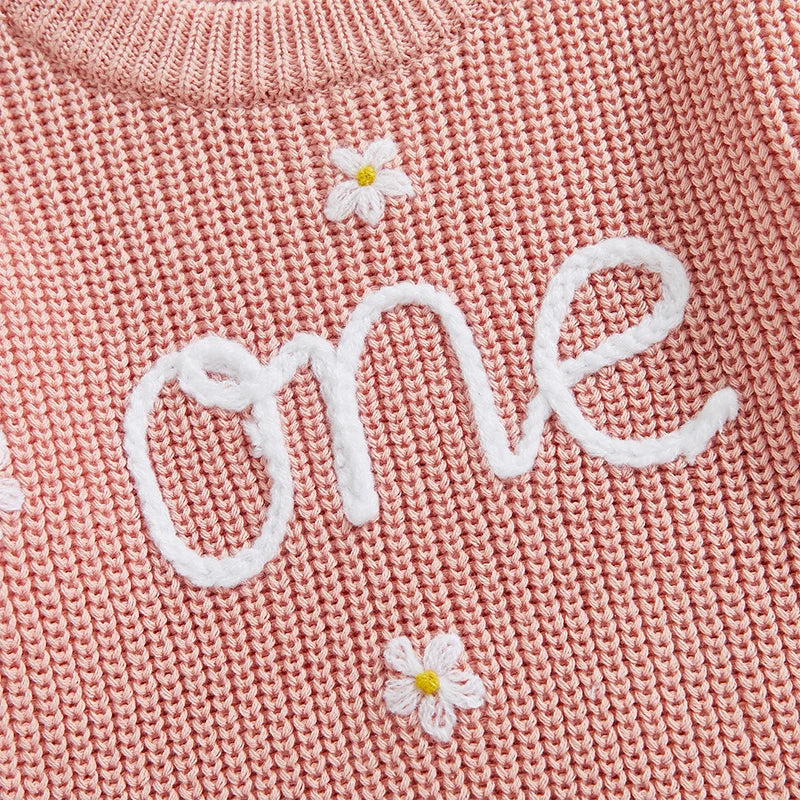 Soft pink baby birthday romper with floral detailing