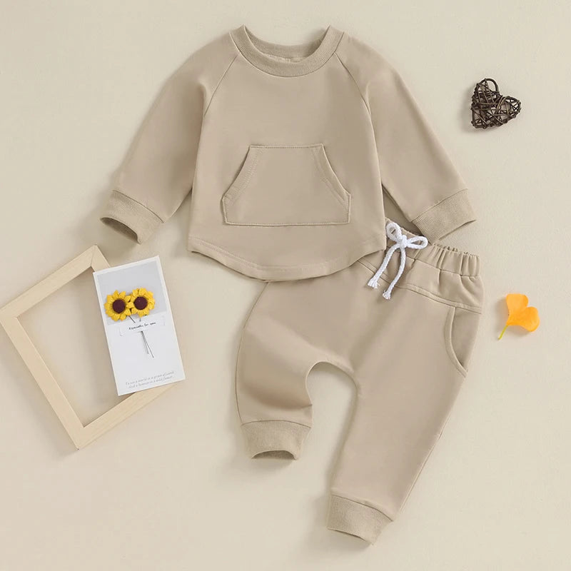 this is a photo of a cream beige baby tracksuit set on a background with a flower and heart