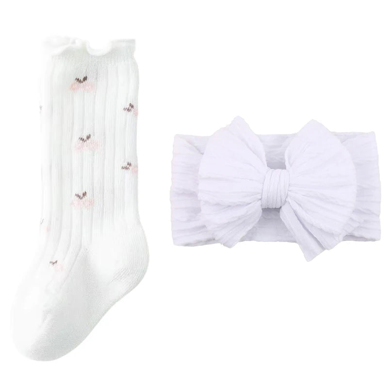 White baby socks with floral details and matching nylon topknot